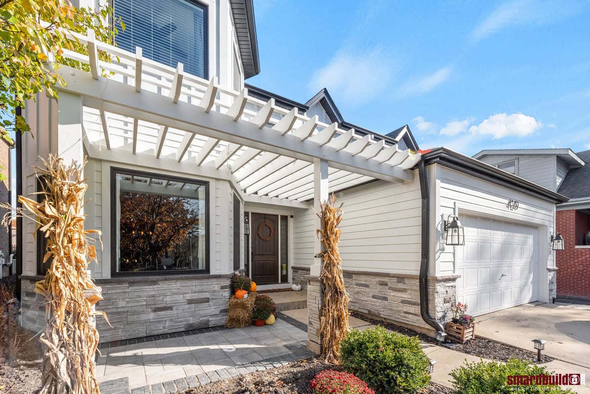 Exterior view of home with white pergola above front porch