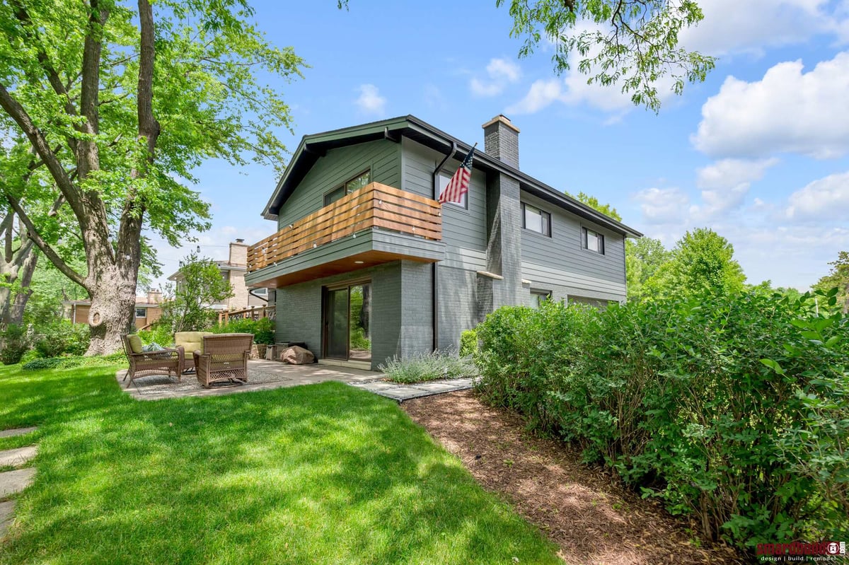 Exterior view of home with dark gray siding and wood deck